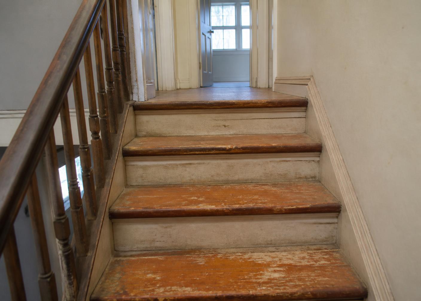 Worn staircase with peeling orange varnish before restoration