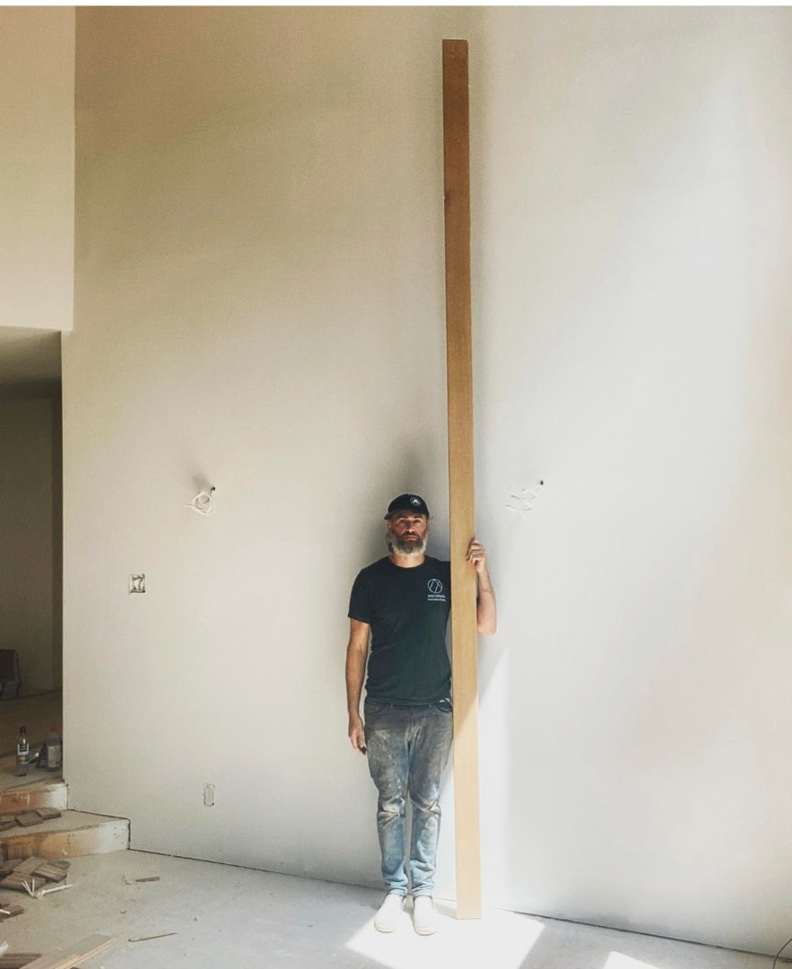 Travis, owner of Avox Craftworks, holding a long white oak plank on a job site