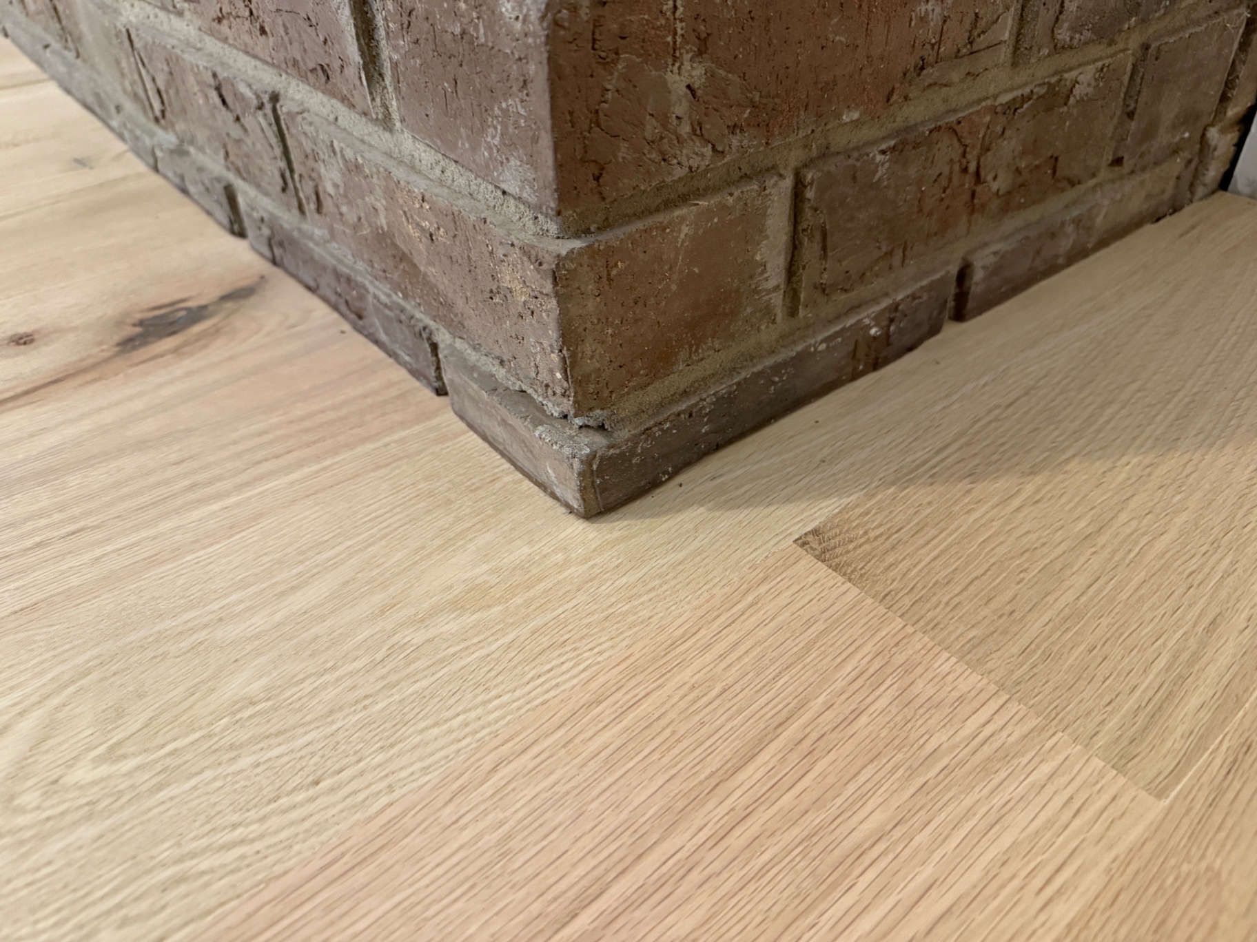 White oak boards woven seamlessly around a brick hearth during a hardwood floor repair
